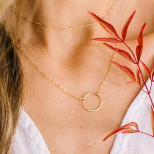 Layered gold stainless steel necklace with round pendant charms on a model