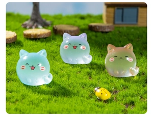 Micro landscape detail of three luminous cat figurines on miniature garden grass