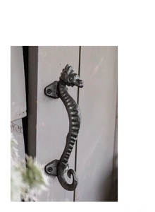 Close-up of vintage seahorse cast iron handle showing rustic texture on grey door