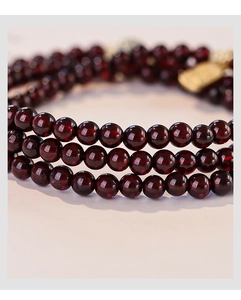Macro shot of natural garnet beads and Hetian jade bracelet with golden metal charms
