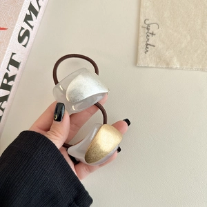 Close-up of gold and silver minimalist hair ties held by hand for sleek ponytail styles
