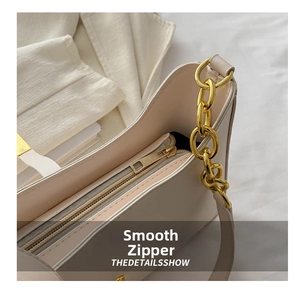 Detail of a beige faux leather bag featuring a gold chain and smooth metal zipper