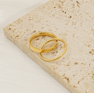 Detail of minimalist gold titanium stackable rings on travertine stone texture