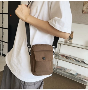 Detailed shot of brown canvas crossbody bag with adjustable strap and snap buckle