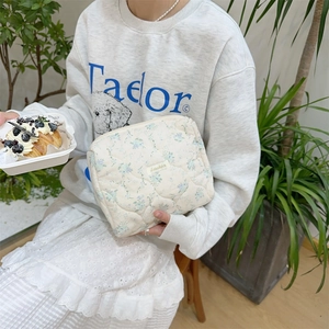 Close-up of quilted floral makeup bag with blue flower patterns and zipper closure
