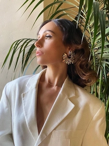 Detailed view of colorful rhinestone sunflower earrings worn by a model in soft light