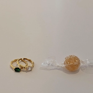 Detail of gold lava rings set featuring emerald green gemstone and clear zircon accents