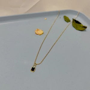 Détail du collier à billes dorées avec pendentif rectangulaire vert émeraude