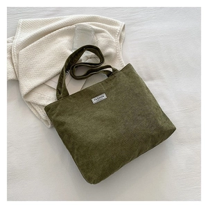 Flat lay detail of dark olive green corduroy tote bag with fashion label on white fabric