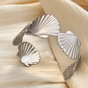 Polished silver shell-shaped open bangle bracelet on luxury champagne silk background