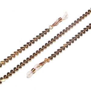 Detailed macro view of golden heart-shaped links and silicone loops on eyewear chain