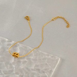 Detail of adjustable gold-tone stainless steel bracelet with chubby letter B pendant
