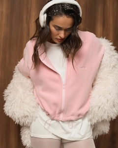 Close-up of pink fleece zipper jacket with letter embroidery layered under white faux fur