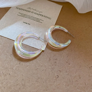 Detail view of colorful iridescent acrylic C-shape earrings with silver pins on cards