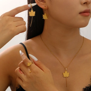Close-up of golden maple leaf jewelry set with tassel chain details on a model