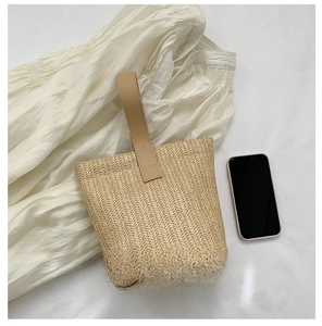 Detail view of woven straw bucket bag showing compact size compared to a smartphone
