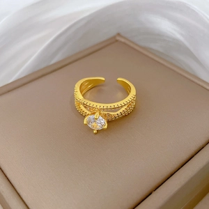 Detail of gold-plated cross ring with a large central zircon and pavé setting on white silk