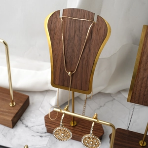 Detailed view of jewelry display rack with wood base and gold metal frame showing necklace