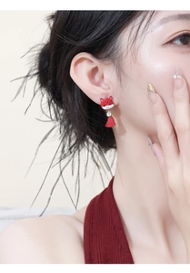 Detail view of red cat earrings with traditional tassel on a female model's ear