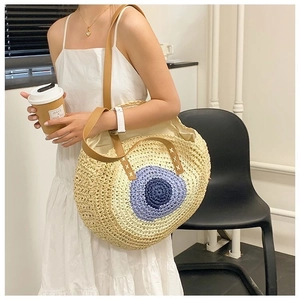 Straw shoulder bag with blue circular pattern and leather straps on white dress model