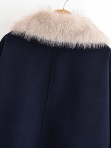 Detailed close-up of navy wool coat with detachable beige faux fur collar on a hanger