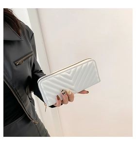Détail d'un long portefeuille blanc zippé avec matelassage en V tenu à la main