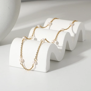 Detailed macro view of 18K gold-plated chain and natural freshwater pearls on a white stand