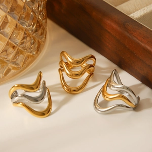 Polished wavy stainless steel rings in gold and silver finish on a stylish display