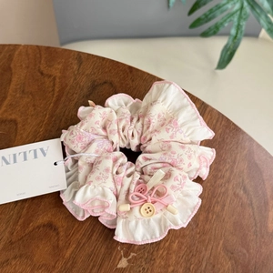 Blumen-Scrunchie mit rosa Rand, Schleife und Knopfdetail auf rustikaler Holzfläche