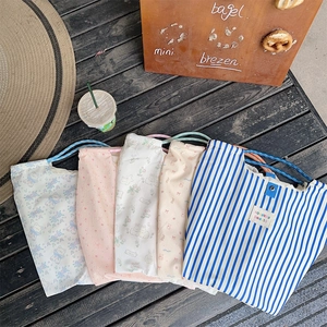 Detail view of five assorted floral and patterned canvas drawstring bags on wood