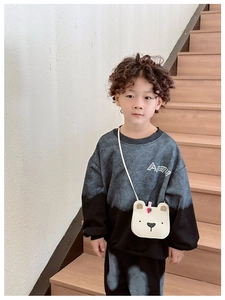 Close-up of a white plush bear crossbody bag styled with a grey tie-dye kid's tracksuit