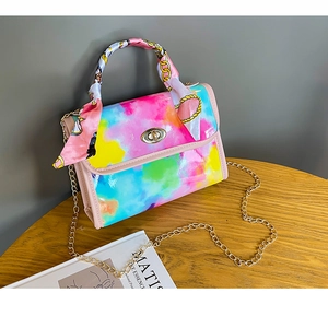 Detail of colorful tie-dye handbag with silk-wrapped handle and golden chain strap