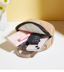 Detailed view of beige quilted circular bag interior showing storage capacity and zipper