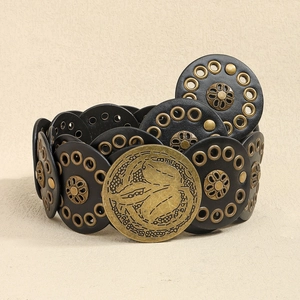 Detail of bohemian black leather belt with hollow rivets and embossed brass buckle