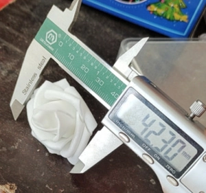 Digital caliper measuring the 42mm diameter of a white foam rose flower head decoration