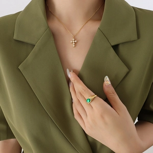 French style gold cross necklace with pearls and green gemstone ring on model