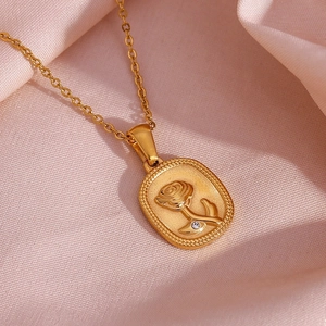 Macro view of 18K gold plated oval rose pendant with crystal inlay on pink silk fabric