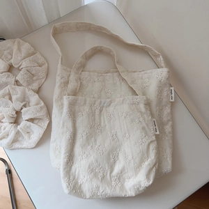 Detail view of cotton shoulder bag with floral embroidery and matching hair scrunchies