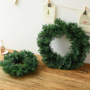 Couronnes de Noël artificielles en pin vert de deux tailles sur une table rustique