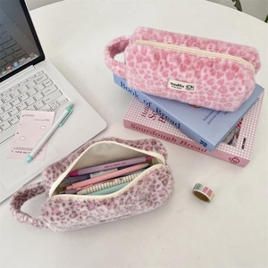 Detailed view of plush leopard print pouches with zippers and handles on a desk