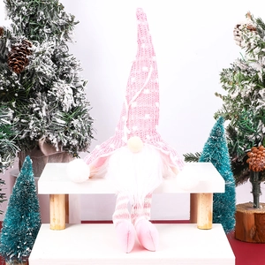 Close-up of a pink knitted Christmas gnome with dots and stripes on a festive display