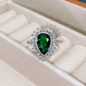 Macro di un anello con zircone verde smeraldo a goccia in una scatola per gioielli in velluto