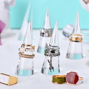 Clear acrylic cone stands displaying assorted pearl and silver rings on a soft blue background