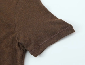 Close-up of the professional stitching and knit cotton texture on brown T-shirt sleeve