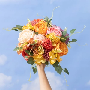 Artificial bouquet with peonies and roses held against a bright blue sky background