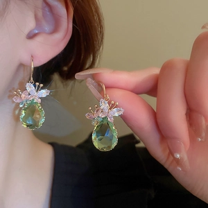 Green teardrop earrings with gold-tone floral zircon accents shown on hand model