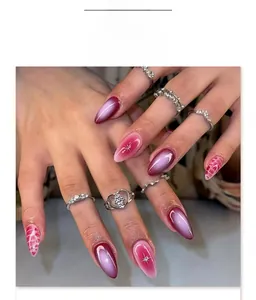 Detail of almond-shaped press-on nails with pink gradient and white star patterns