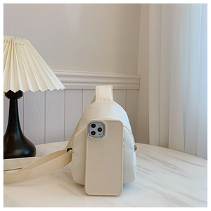 Mini cream crossbody bag shown next to a smartphone to demonstrate its compact size