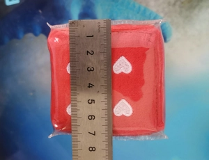 Detail shot showing 7cm dimensions of plush red car dice with heart embroidery