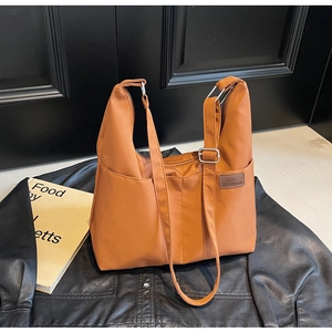 Detail shot of brown canvas tote bag with fashion label on black leather jacket background